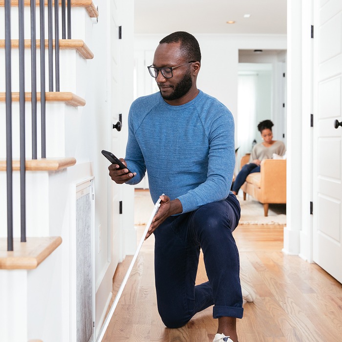 TVA Energy Expert measures a home's HVAC air filter, using a phone during an energy assessment for optimal heat pump performance.