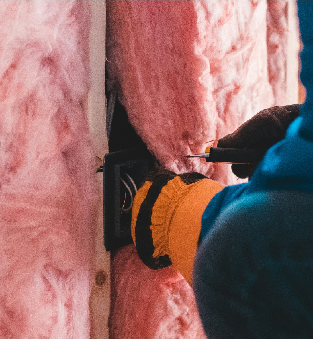 TVA Energy Expert installing an electrical box in a wall with pink fiberglass insulation, crucial for smart home technology and energy savings.