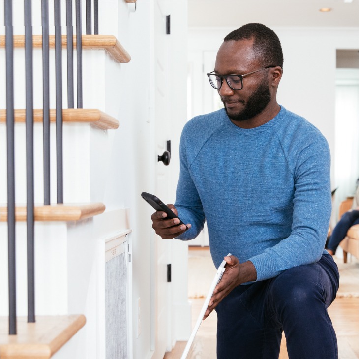 Man inspecting an HVAC heat pump air filter, using a smartphone for guidance on optimal system performance.