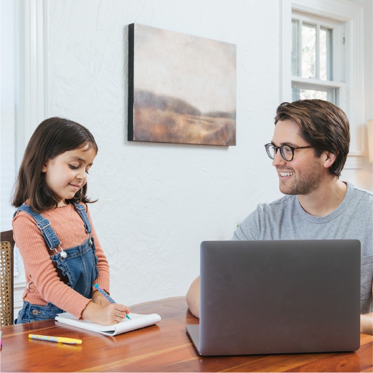A father smiles at his daughter drawing at a table, highlighting a comfortable, energy-efficient home environment.