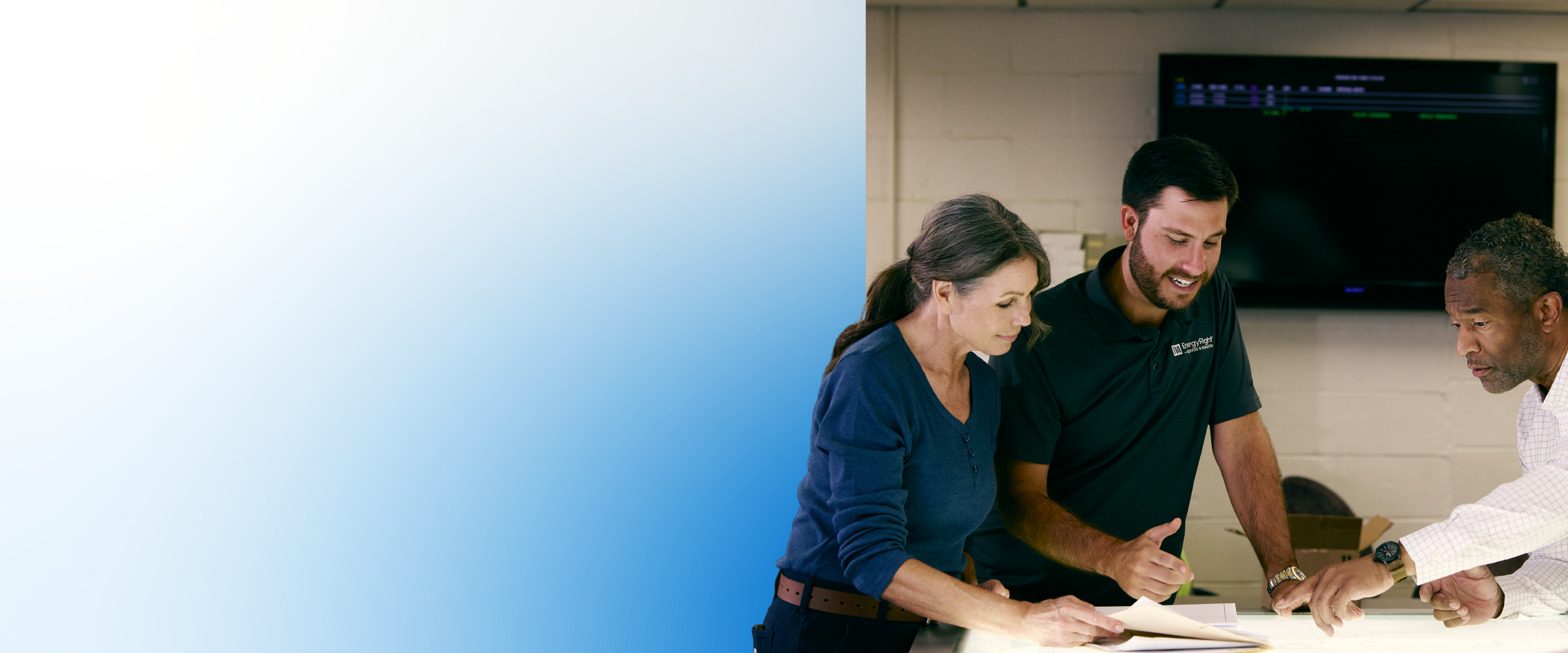 A TVA Energy Expert in an EnergyRight shirt reviews documents with a woman and another man, discussing energy efficiency solutions.