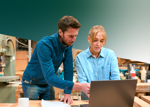 Two TVA Energy Experts review energy-saving strategies on a laptop in a commercial workshop.
