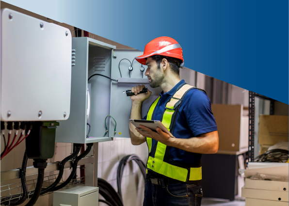 TVA Energy Expert in hard hat and vest inspects complex electrical systems with a flashlight and tablet, ensuring peak energy efficiency.