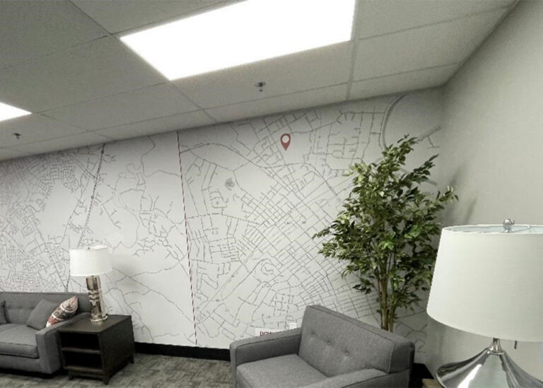 Modern office space featuring a large wall mural of a community map with a red location pin, under bright LED lighting, reflecting TVA's local reach.