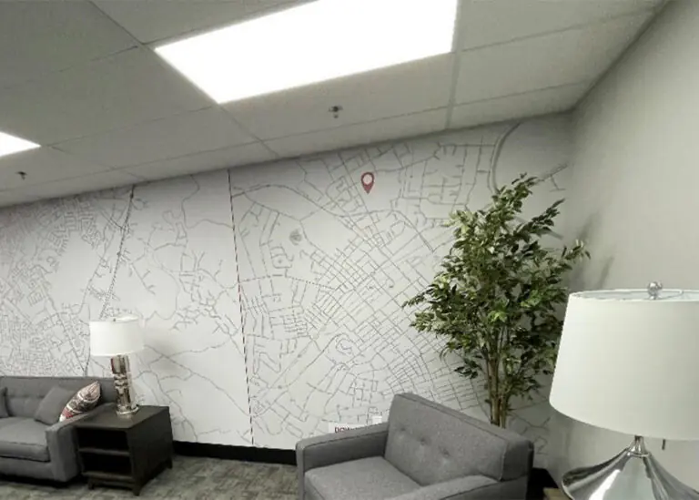 Modern office space featuring a large wall mural of a community map with a red location pin, under bright LED lighting, reflecting TVA's local reach.